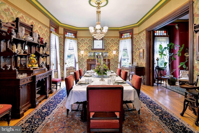 dining area featuring a chandelier, hardwood / wood-style flooring, plenty of natural light, and ornamental molding