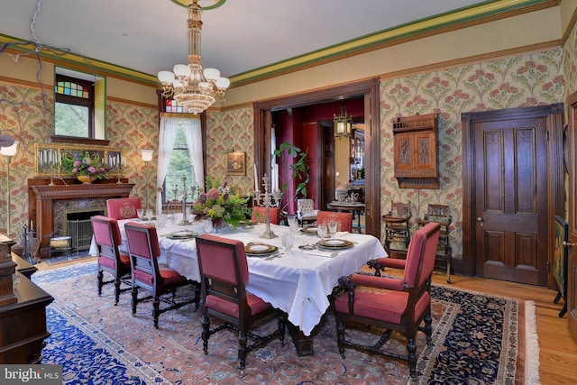 dining area with a chandelier, light hardwood / wood-style floors, ornamental molding, and a high end fireplace