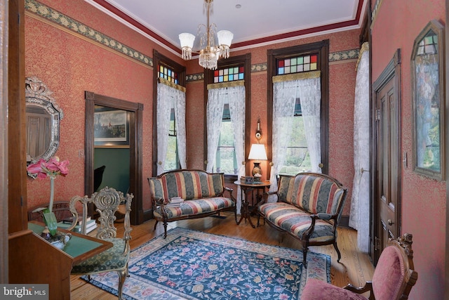 living area with hardwood / wood-style floors, a notable chandelier, and ornamental molding