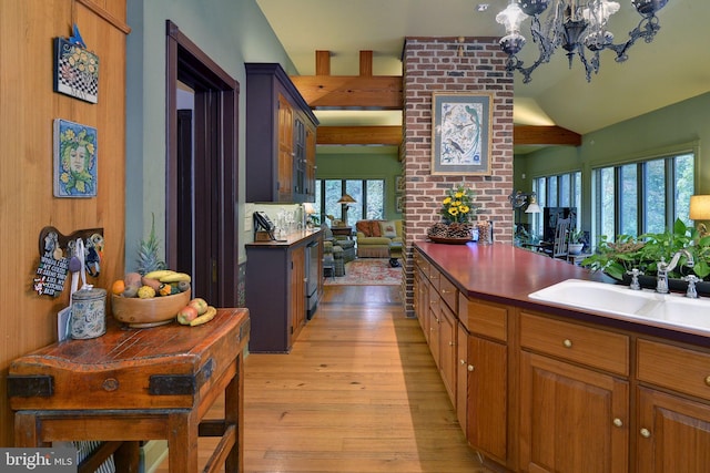 kitchen featuring a chandelier, light hardwood / wood-style floors, lofted ceiling, and sink