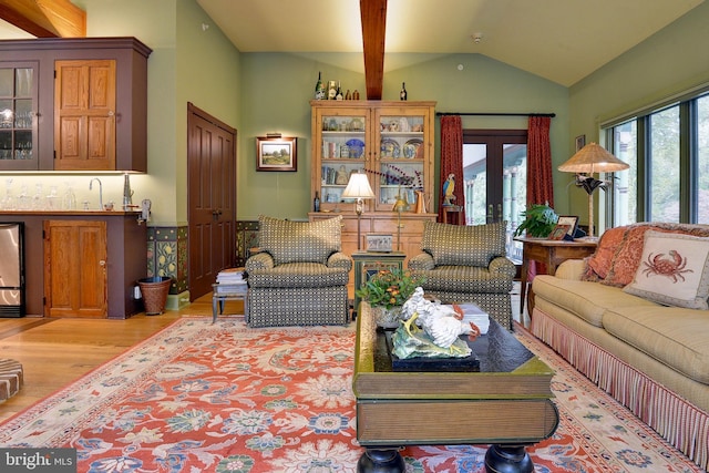 living room featuring vaulted ceiling with beams, light wood-type flooring, and french doors