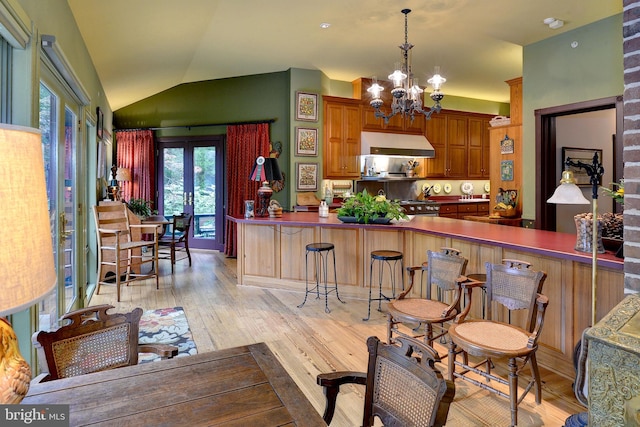 kitchen featuring kitchen peninsula, light hardwood / wood-style flooring, pendant lighting, and lofted ceiling