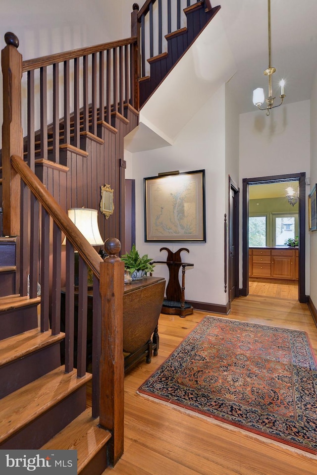 stairs featuring hardwood / wood-style floors, high vaulted ceiling, and a notable chandelier