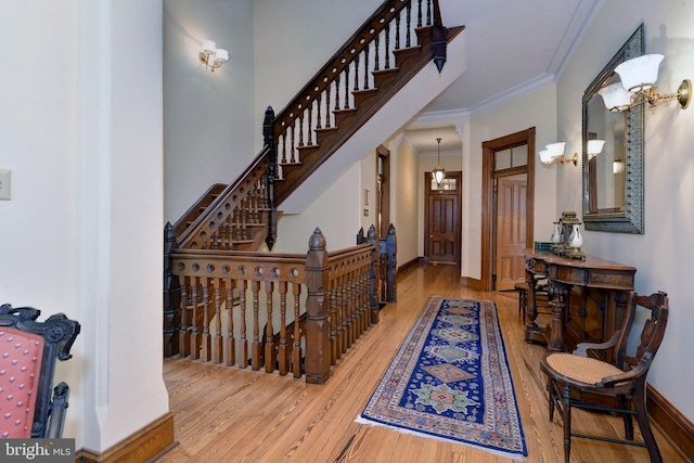 interior space with an inviting chandelier, wood-type flooring, and ornamental molding