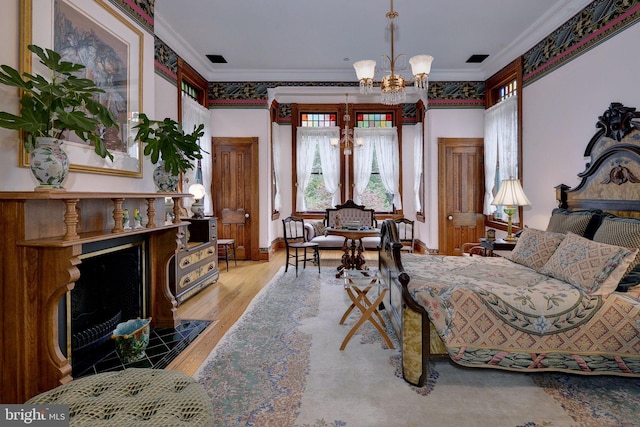 bedroom with a tile fireplace, light hardwood / wood-style floors, an inviting chandelier, and ornamental molding