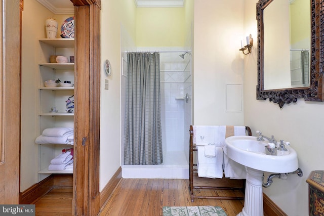 bathroom with a shower with curtain, hardwood / wood-style flooring, and ornamental molding