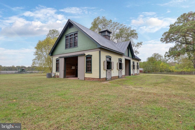 exterior space featuring central AC unit, an outbuilding, and a lawn