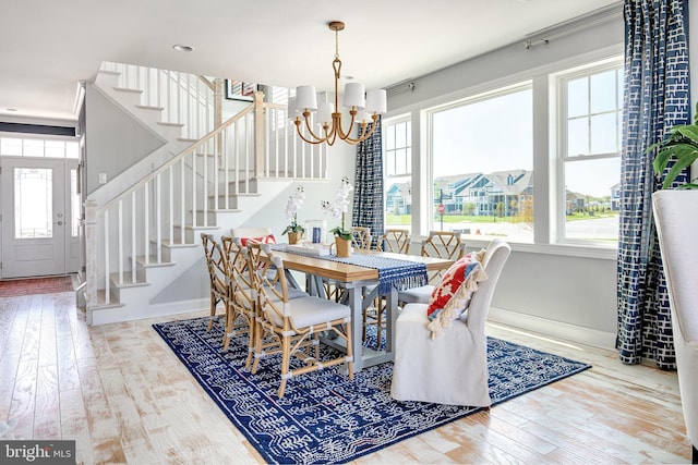 dining space featuring light wood-type flooring, a notable chandelier, and a wealth of natural light