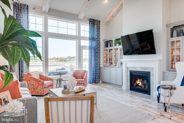 living room with a wealth of natural light, a premium fireplace, and beamed ceiling