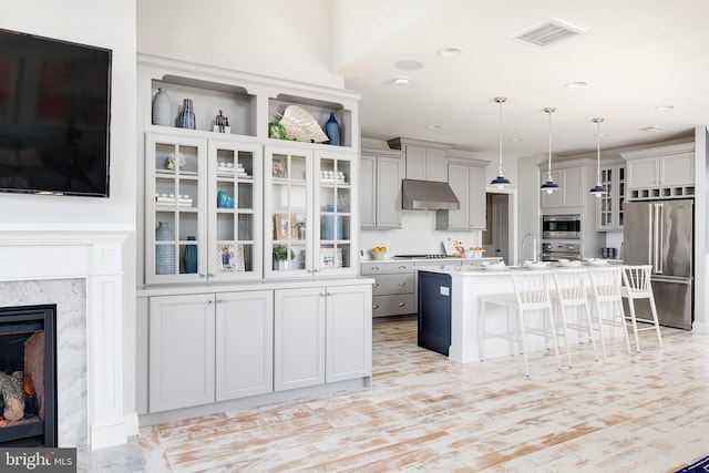 kitchen with pendant lighting, appliances with stainless steel finishes, a breakfast bar, a center island with sink, and tasteful backsplash