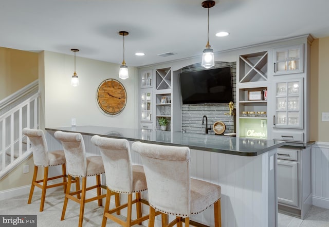 bar with hanging light fixtures, sink, and light carpet