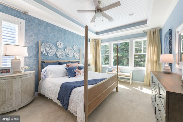 carpeted bedroom featuring a raised ceiling, ornamental molding, and ceiling fan