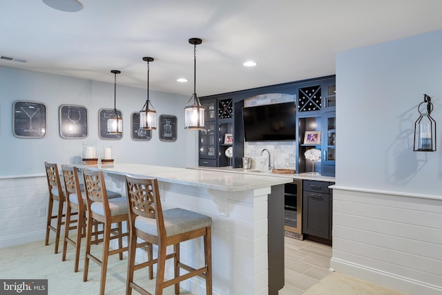 bar featuring sink, light tile floors, light stone countertops, beverage cooler, and decorative light fixtures