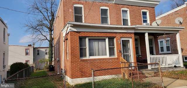 view of front of home featuring a porch, brick siding, and a fenced front yard