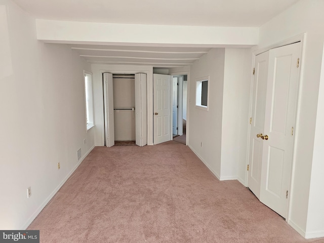 unfurnished bedroom with light carpet and beam ceiling