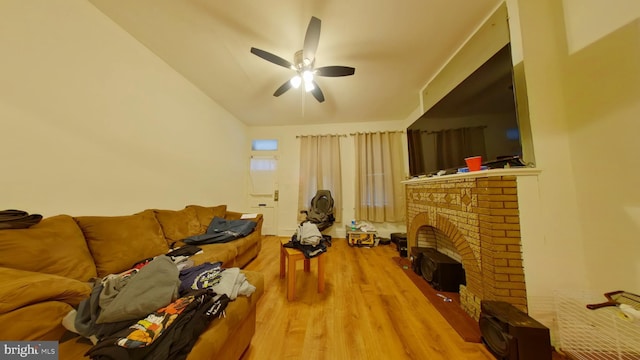 living room featuring lofted ceiling, light hardwood / wood-style flooring, ceiling fan, and a brick fireplace