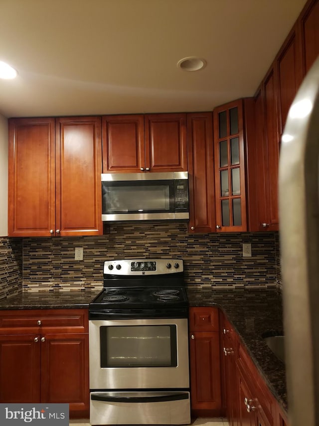 kitchen with backsplash, appliances with stainless steel finishes, and dark stone countertops