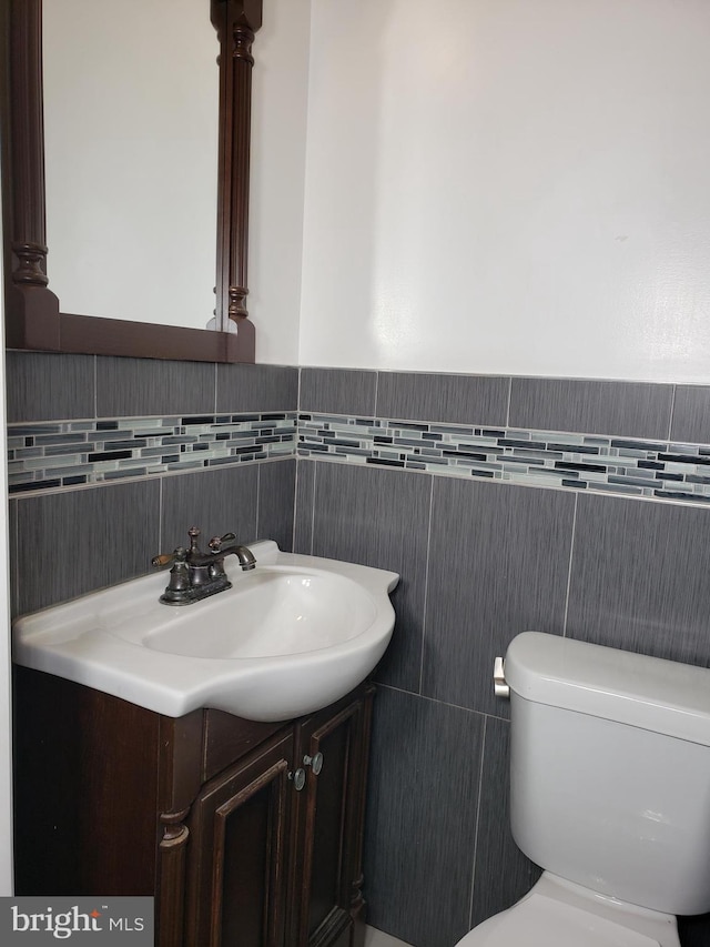 bathroom featuring vanity, toilet, and tile walls