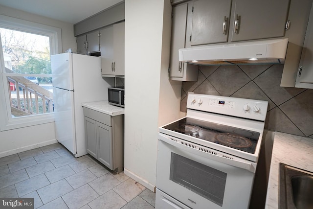 kitchen with white appliances, gray cabinetry, backsplash, and light tile floors