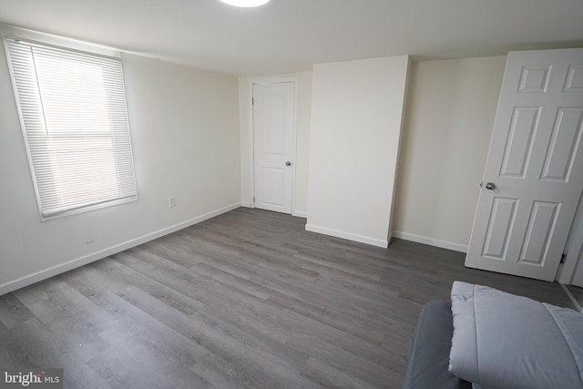 unfurnished bedroom featuring multiple windows and dark hardwood / wood-style flooring