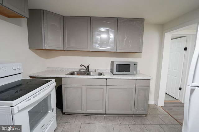 kitchen featuring gray cabinetry, white appliances, light tile flooring, and sink