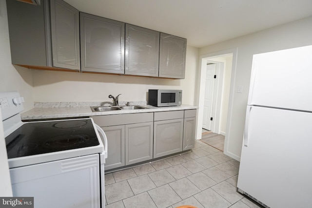 kitchen featuring white appliances, light hardwood / wood-style flooring, sink, and gray cabinets