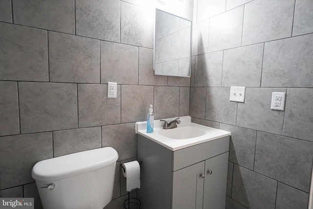 bathroom with tile walls, toilet, and vanity with extensive cabinet space