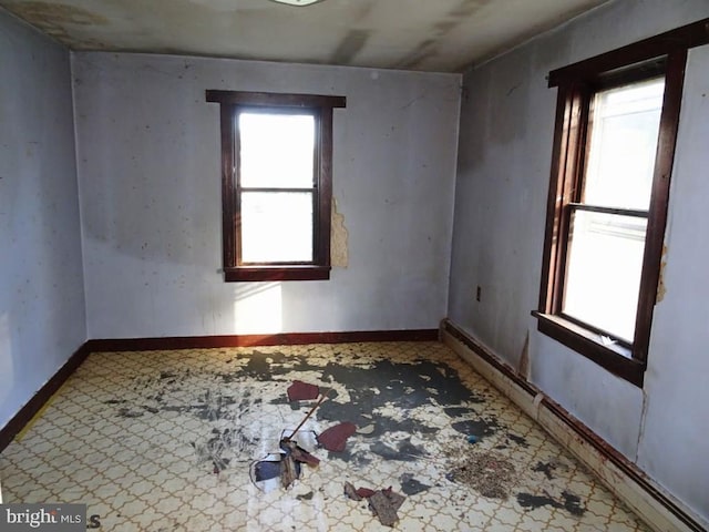 empty room featuring plenty of natural light and a baseboard radiator