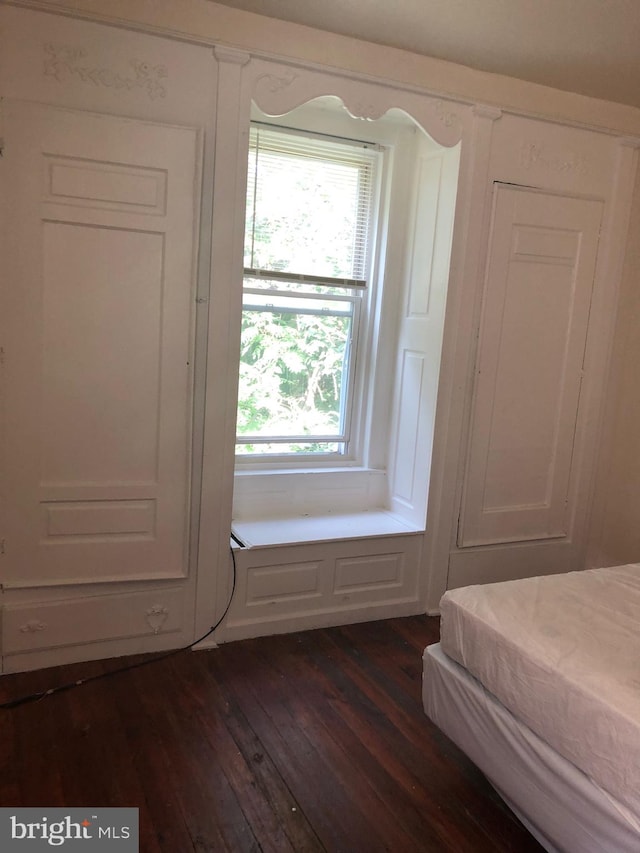 unfurnished bedroom with dark hardwood / wood-style flooring and multiple windows