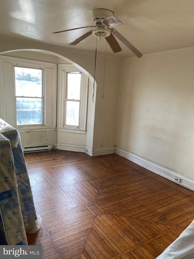 unfurnished room featuring baseboard heating, dark parquet flooring, and ceiling fan