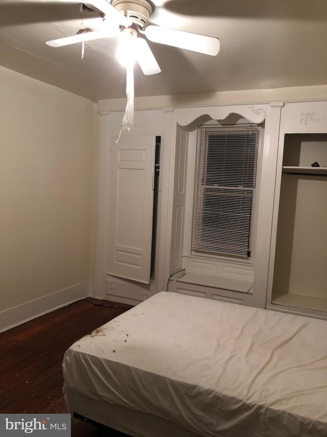 unfurnished bedroom with ceiling fan and dark wood-type flooring