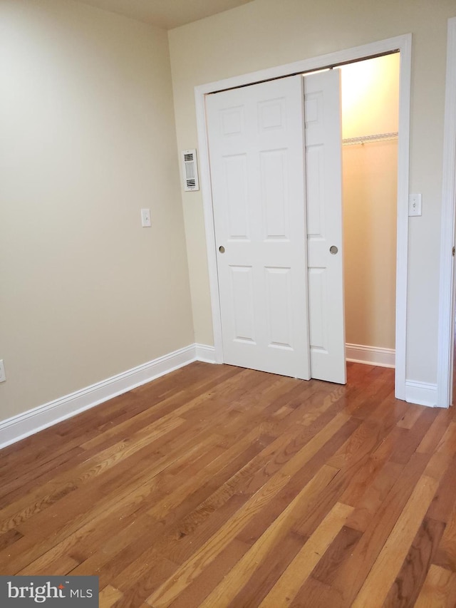 unfurnished bedroom featuring a closet and hardwood / wood-style flooring