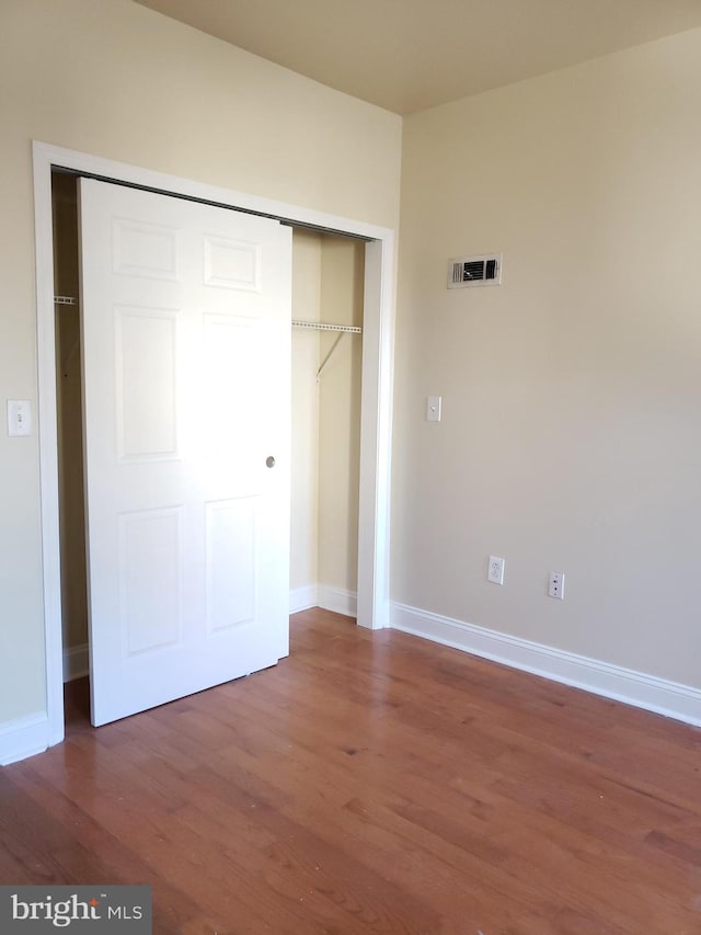 unfurnished bedroom featuring a closet and dark hardwood / wood-style flooring