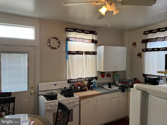 kitchen with ceiling fan, tile counters, white cabinets, and white range oven