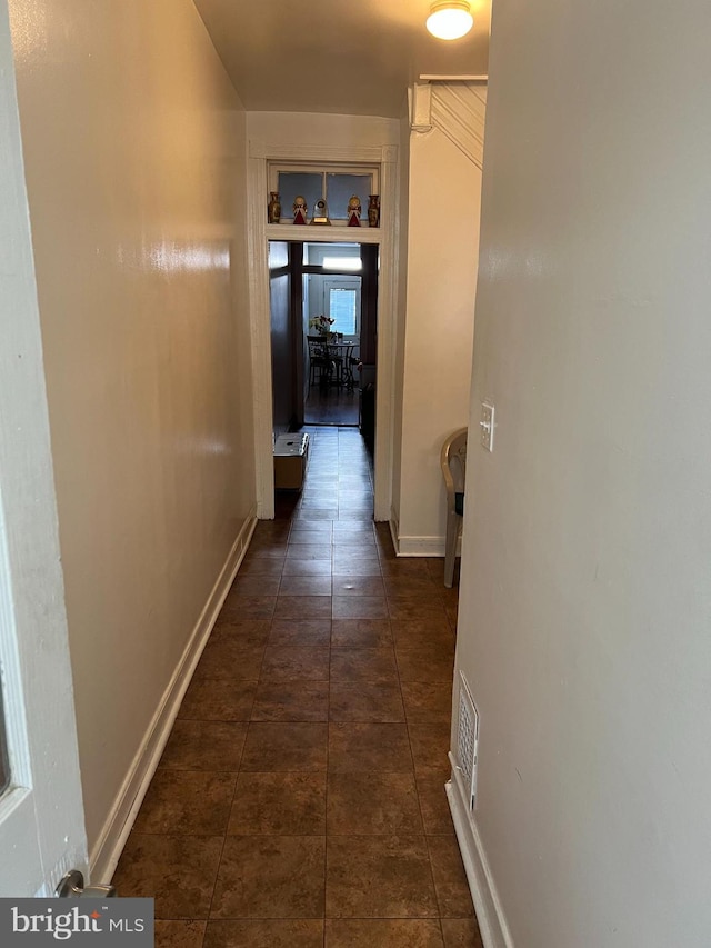 hall with dark tile flooring