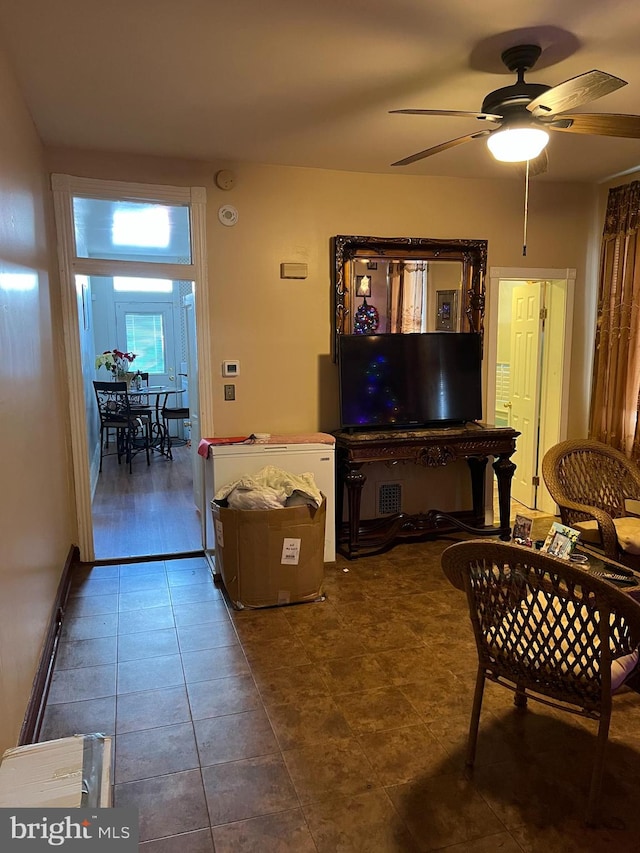 living room with ceiling fan and dark tile floors