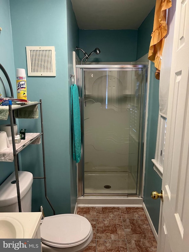 bathroom with a shower with door, toilet, and vanity