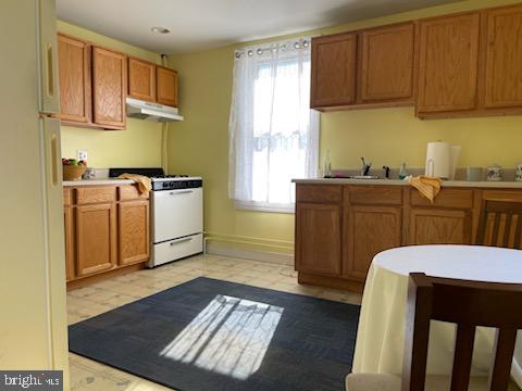 kitchen featuring light tile floors, plenty of natural light, white fridge, and gas stove