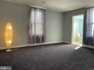 unfurnished room featuring dark carpet