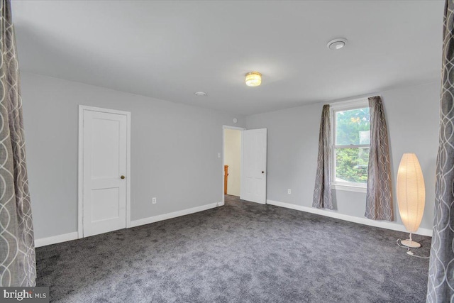 spare room with dark colored carpet