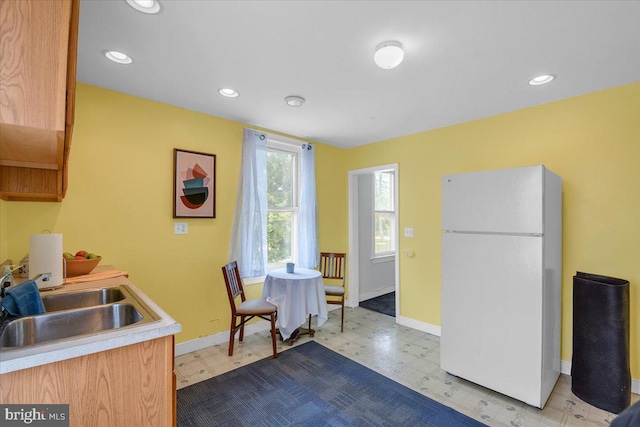 kitchen featuring white refrigerator, light tile floors, and sink