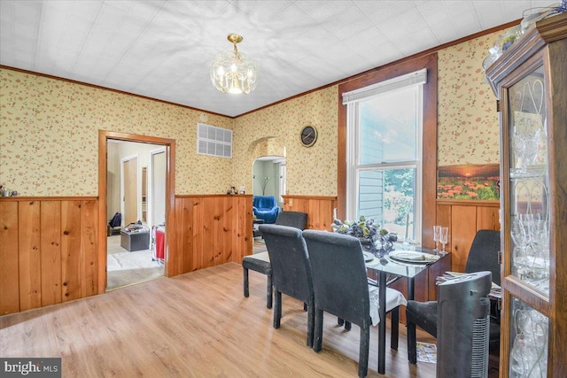 dining space with crown molding, a notable chandelier, and light wood-type flooring