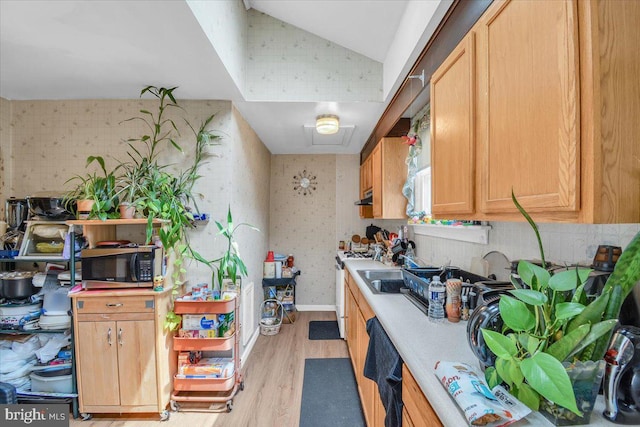 kitchen featuring light hardwood / wood-style floors, vaulted ceiling, white gas range oven, dishwasher, and sink