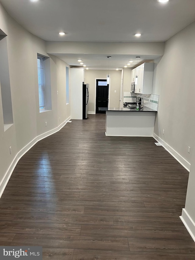 kitchen with white cabinetry, dark hardwood / wood-style floors, appliances with stainless steel finishes, and kitchen peninsula