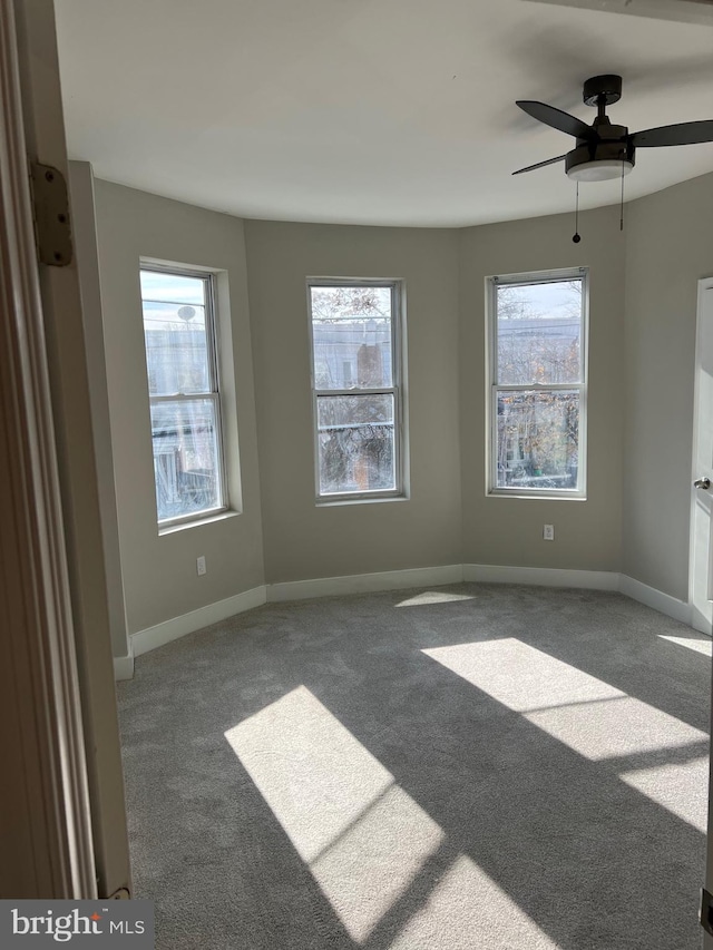 spare room with plenty of natural light, ceiling fan, and dark colored carpet