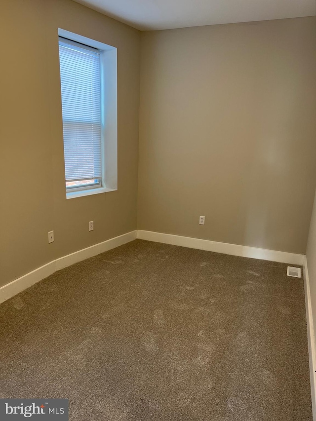 spare room featuring dark carpet