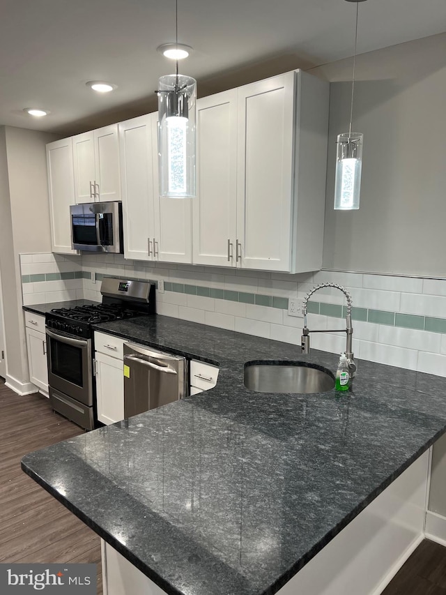 kitchen featuring pendant lighting, stainless steel appliances, tasteful backsplash, and dark wood-type flooring