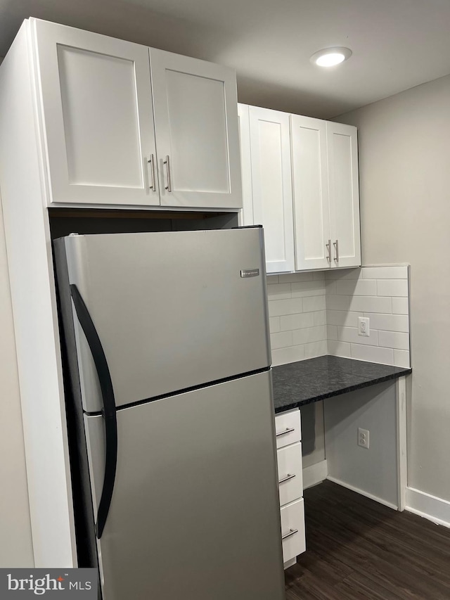 kitchen with stainless steel fridge, white cabinets, dark wood-type flooring, and tasteful backsplash