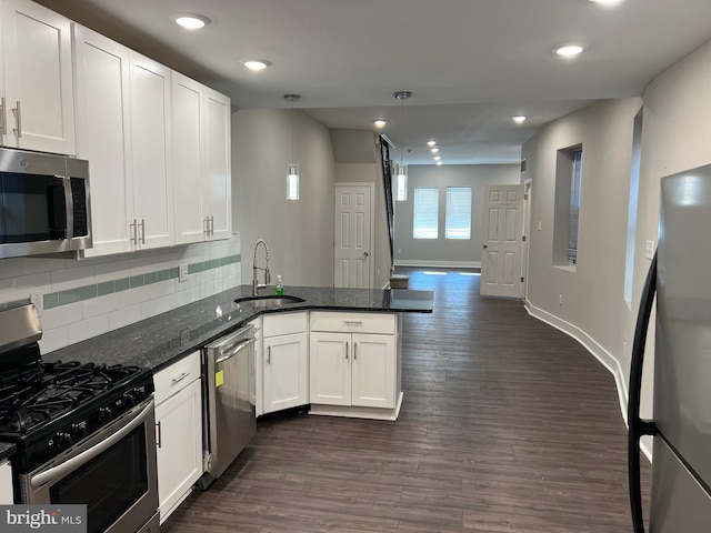 kitchen featuring dark hardwood / wood-style floors, sink, stainless steel appliances, dark stone countertops, and pendant lighting