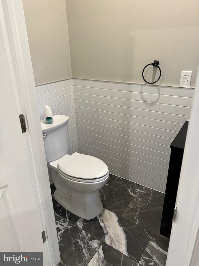 bathroom with tile walls, tile floors, and toilet